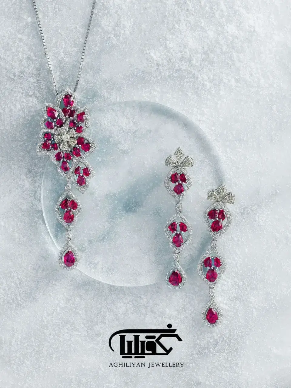 ruby-&-zirconia-center-stone-jewelry-set-3644 نیم ست یاقوت قرمز و تخمه زیرکونیوم 3644 شامل آویز و گوشوارههای بلند با نگینهای یاقوت سرخ تراش اشک و الماس برلیان روی زمینه یخی